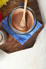 Melted chocolate in glass bowl, on wooden background