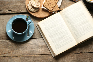 Open book and snack on wooden table background