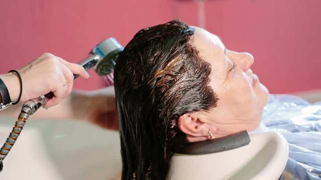 Hairdresser wash head to the client with dyed hair. Video full hd.