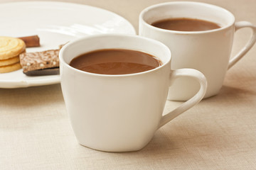 Two cups of hot chocolate with cookies