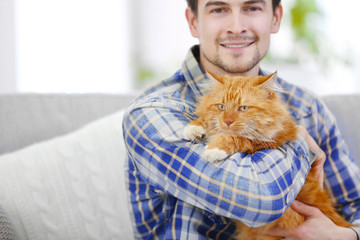 Young man with fluffy cat sitting on a sofa