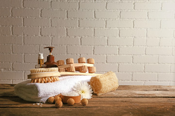 Variety of natural bath tools on wooden table, on bricks wall background
