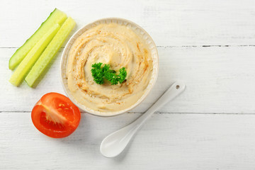 Ceramic bowl of tasty hummus with parsley on table