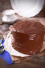 Chocolate cake with two spoons and blue tablecloth on a wooden boards background