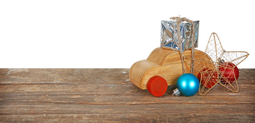Wooden toy car with gift box and toys on a table over white background
