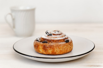  Cinnamon roll with raisins in a ceramic saucer