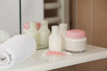 Fototapeta na wymiar White towel with cream and ear sticks in a shelf in bathroom