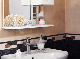 Bathroom interior with sink, shelf, towel and liquid soap