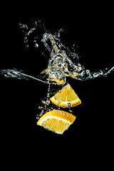 Orange slices falling into the water close-up, macro, splash, bubbles, black background
