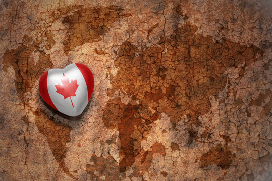 heart with national flag of canada on a vintage world map crack paper background. concept