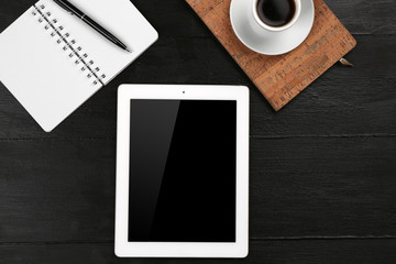 Digital tablet with cup of coffee and notebook on wooden table, closeup