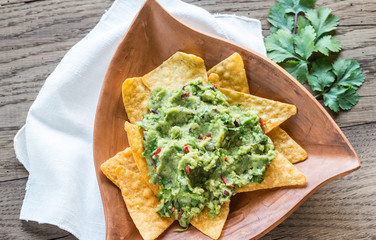 Guacamole with tortilla chips on the wooden background