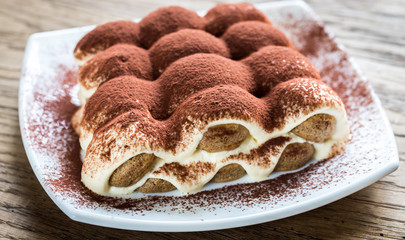 Tiramisu on the plate on the wooden background