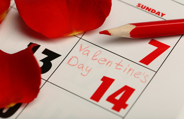 Calendar with date of February 14 and rose flower petals. Valentines day concept