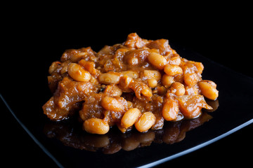 Baked beans in tomato sauce on a black plate