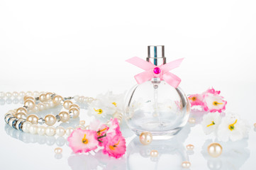 Perfume for women, pearl white beads, jewelry, pink flowers. Bottle of perfumes for women. Romantic concept on white background.