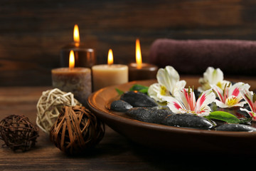 Fototapeta na wymiar Spa wooden bowl with water, flowers and stones on wooden background