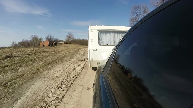 Green car with  caravan ,trailer go on  dirt road