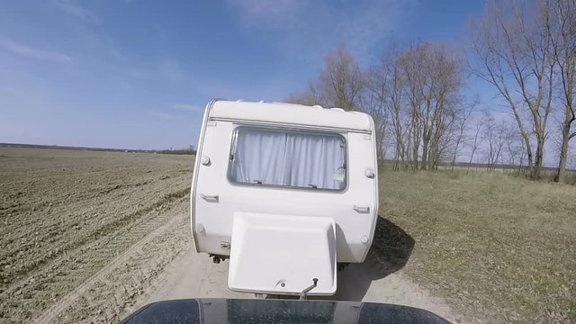 White  caravan ,trailer go  on  dirt road.