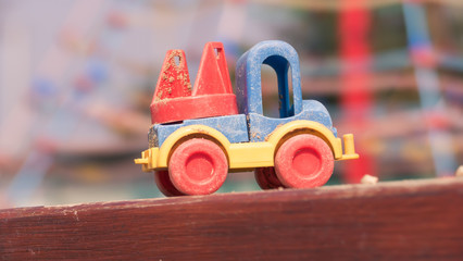 Fototapeta premium A detail of a color plastic truck toy during lovely spring time on the playground for kids - color toned image - focus on cabin