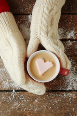 Woman hands in mittens holding a cup of coffee