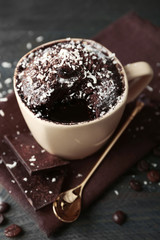 Chocolate fondant cake in cup on wooden table closeup