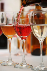 Red wine pouring into glasses, closeup