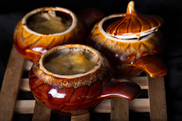 Ceramic pots with the baked meat and cheese on a wooden support