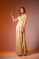 Fototapeta premium Elegant Woman in Golden Dress with wineglass