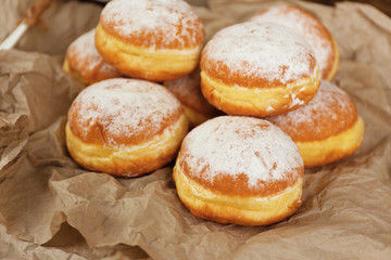 Obraz na płótnie Canvas Delicious donuts with powdered sugar on parchment closeup