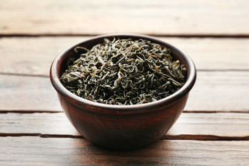 Fototapeta premium Green tea in a round bowl on wooden table, close up