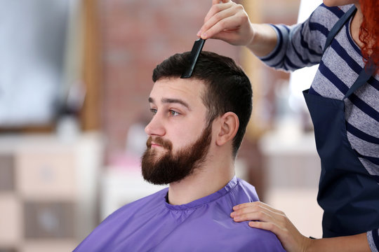 Professional hairdresser making new haircut  her handsome client