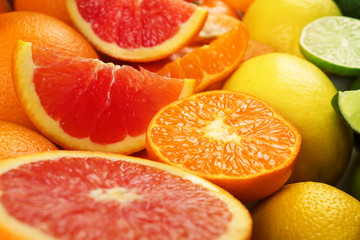 Colorful mixed citrus fruit sorted and lined up in rows with slices and halves, close up