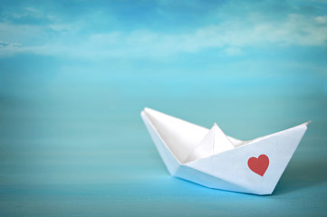 Paper origami boat on blue background with copy space. Love concept.