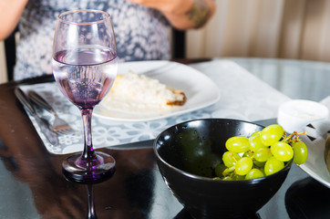 Classy dinner table setting with black bowl of green grapes in front focus