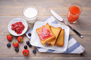 Sweet rusks, strawberry jam, milk and juice of blood oranges