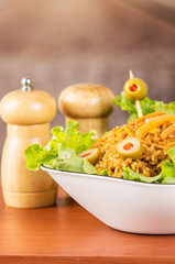 Closeup classy presentation salad, rice and olives in artistic white plate with abstract background, salt pepper shakers sitting on table