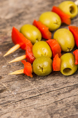 Vegetable skewers of olives and capiscum lying on grey stone surface as seen from above