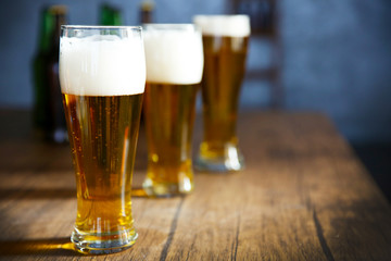 Three glasses of light beer on wooden table