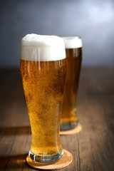 Two glasses of light beer on wooden table