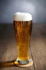 Glass of light beer on wooden table