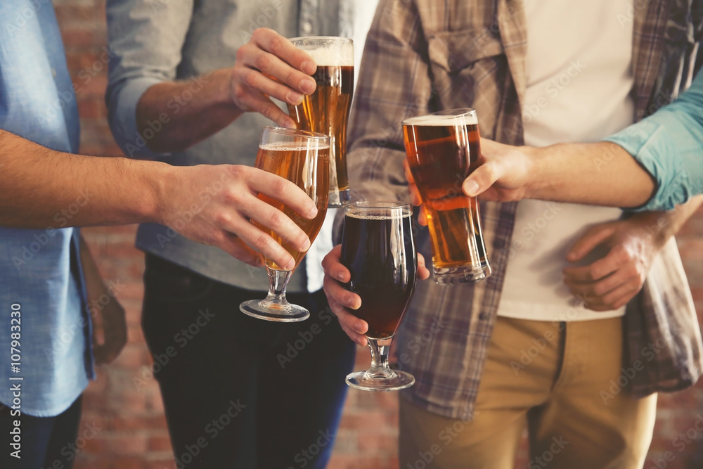 Canvas Prints Male group clinking glasses of dark and light beer on brick wall background