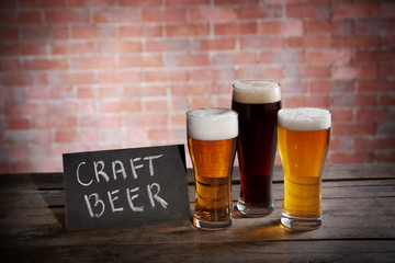 Glasses with different sorts of craft beer on brick wall background