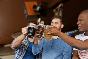 Group of happy friends drinking beer in pub