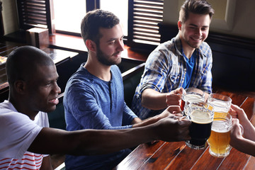 Group of happy friends drinking beer in pub