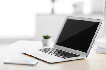 Workplace with laptop and mobile phone indoors