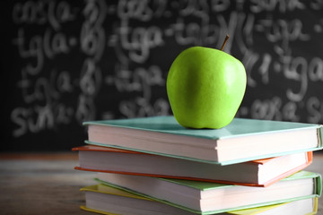 Few books with green apple on table