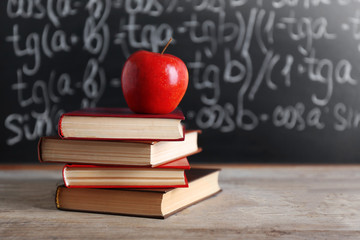 Few books with red apple on table