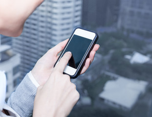 Closeup of female hands using a smart phone. City background.