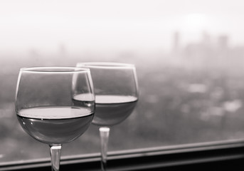 Pair of wine glasses next to window. 